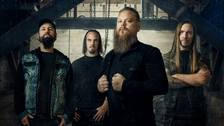 Fire menn med alvorlige ansiktsuttrykk står innendørs mot en industriell bakgrunn i denne sentrale scenen; en av dem er iført dongerivest, en annen har langt hår og skjegg - noe som fanger den tøffe stemningen i Ringes Ronny.