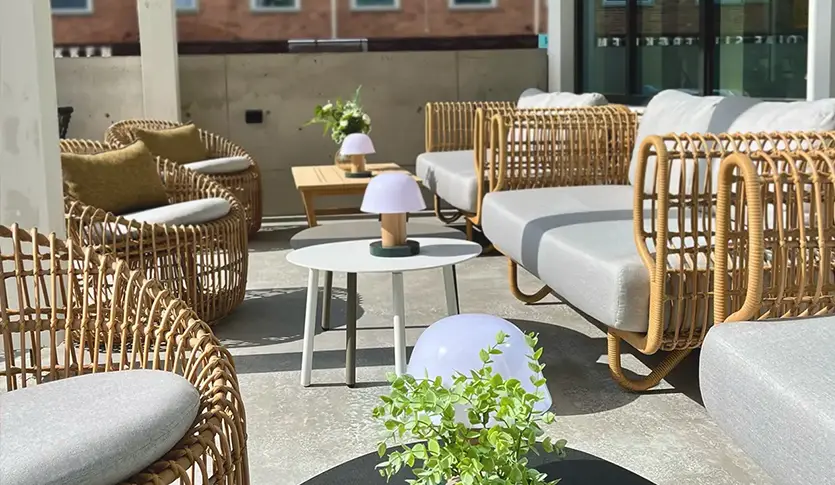 Uteservering på Central Restaurant og Bar med kurvstoler, små hvite bord, og potteplanter på en solrik terrasse.