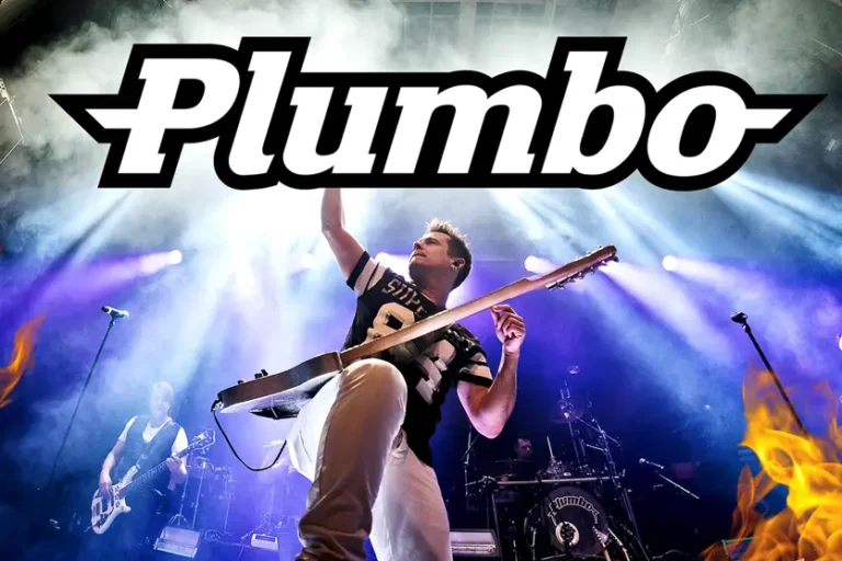 En musiker spiller energisk gitar på scenen, med bandnavnet "Plumbo" fremtredende ovenfor. Det er Hallvard Dyrnes – Første Show, og bakgrunnen har levende scenebelysning og flere bandmedlemmer som opptrer.